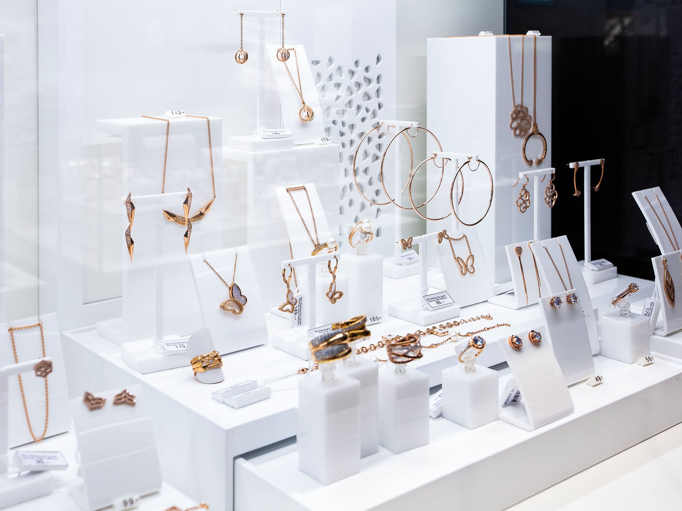 Klassische Umsetzung eines Schmuckdisplays mit unterschiedlichen Einzelaufstellern für Schmuckstücke. Materialmix aus Holz lackiert und farbigem Plexiglas.