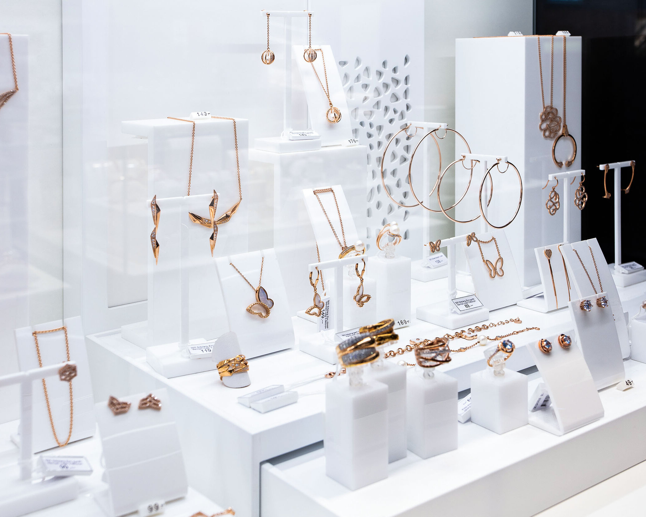 Klassische Umsetzung eines Schmuckdisplays mit unterschiedlichen Einzelaufstellern für Schmuckstücke. Materialmix aus Holz lackiert und farbigem Plexiglas.